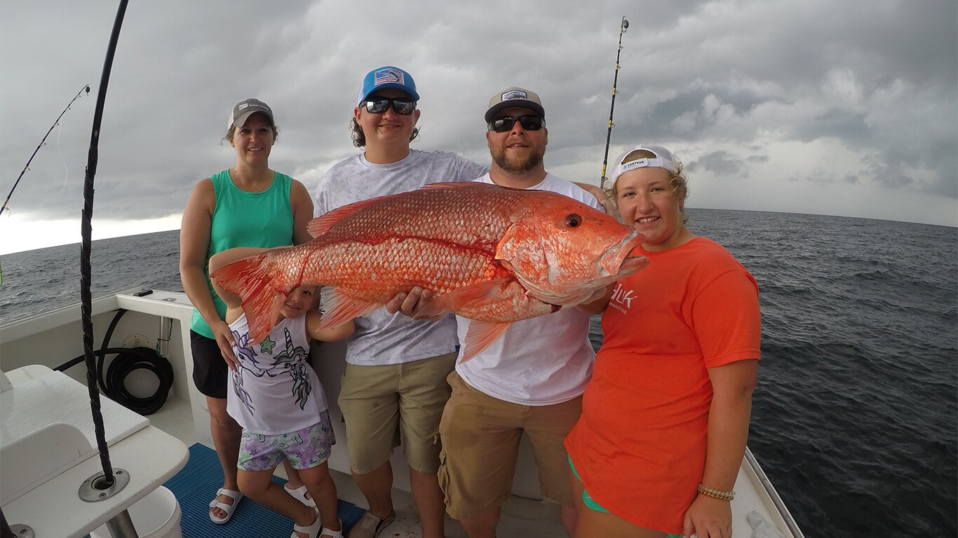 Josh Fowler et sa famille tiennent un gros poisson sur le bateau de pêche Yankee Star